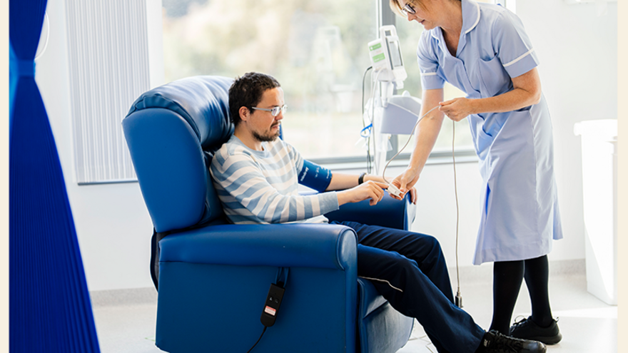 A nurse is taking the pulse of a patient who is reclining in a chair