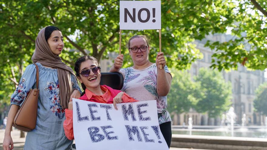 Three women with signs demonstrating in a park