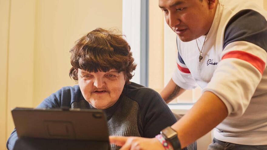 A man showing someone how to use a laptop 