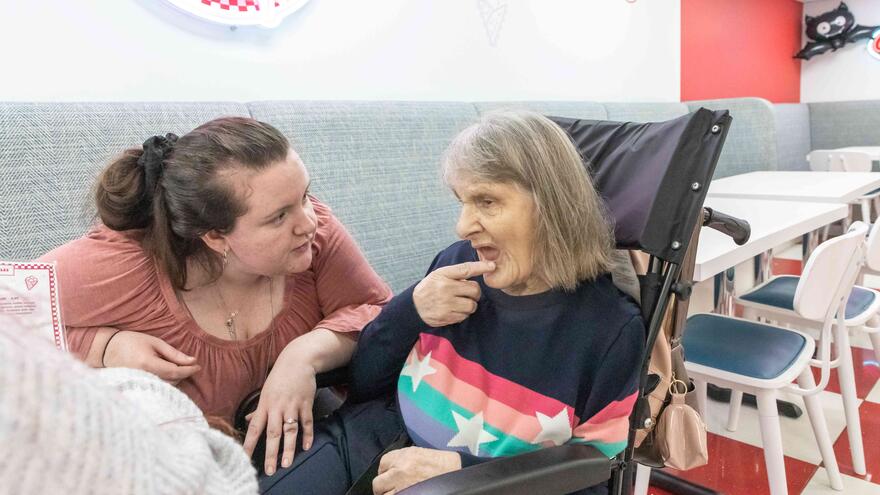 a woman is talking to another woman in a wheelchair
