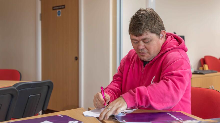 A man is sitting in an office filling out a form at a desk