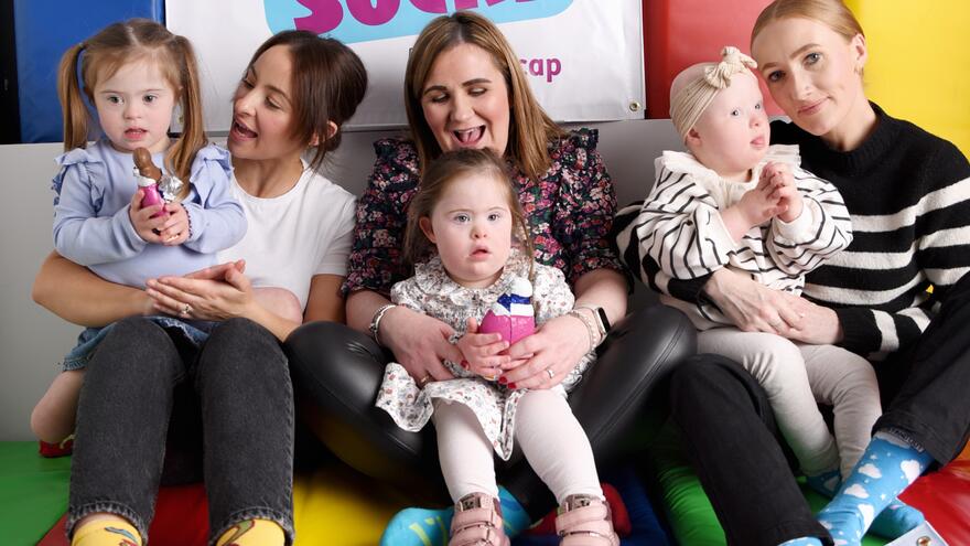 Three mothers sitting on the floor with their children