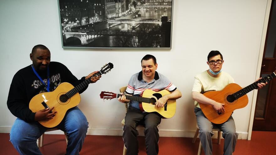 Three men sat down playing guitars.