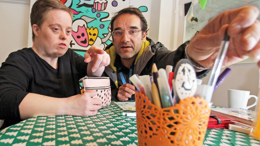 Two people sat at a table, drawing