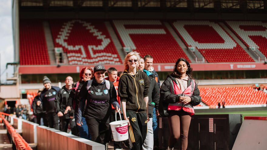 A group of people on a sponsored walk, carrying donation buckets.