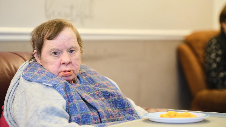 A woman sits alone at a table with a plate of food on it looking sad