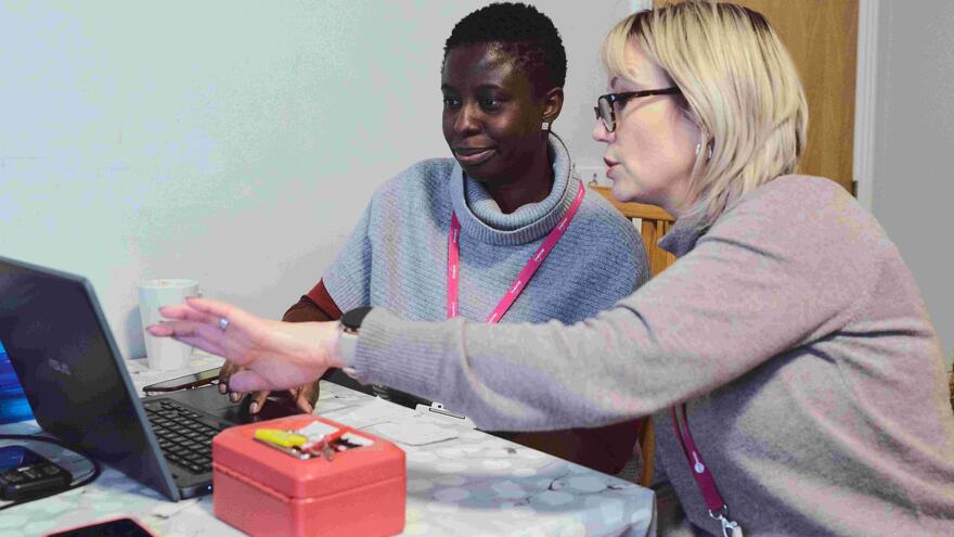 A girl being shown how to use a laptop