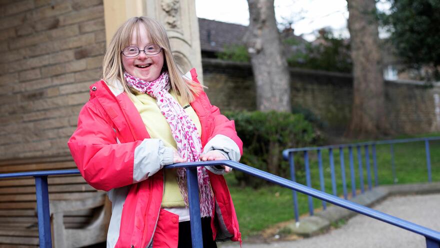 Girl with Down syndrome standing at the top of some steps into a building