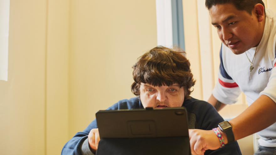 A man is being shown how to use a laptop
