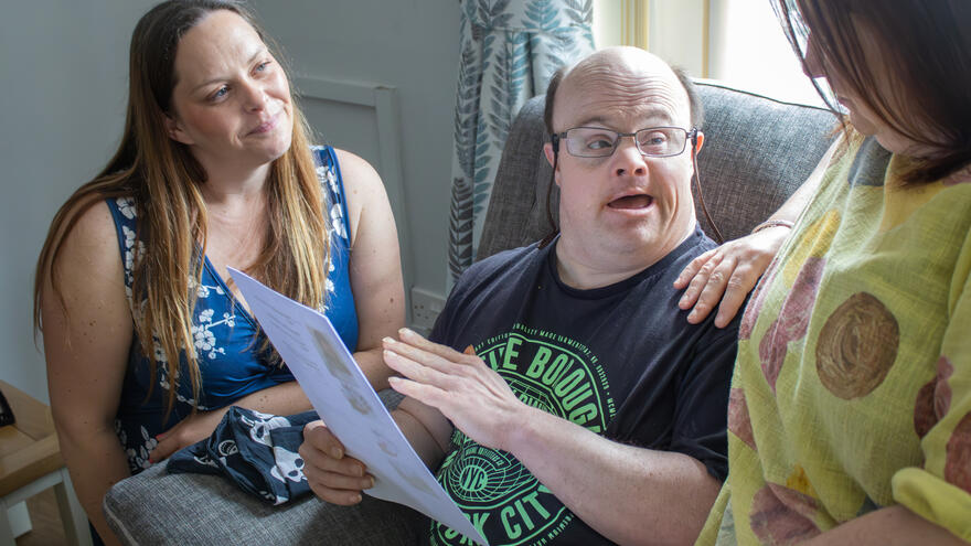 A carer and Trust Relationship Manager, Stacy, sat either side of Nick, reviewing an easy ready document together and talking it through with him.