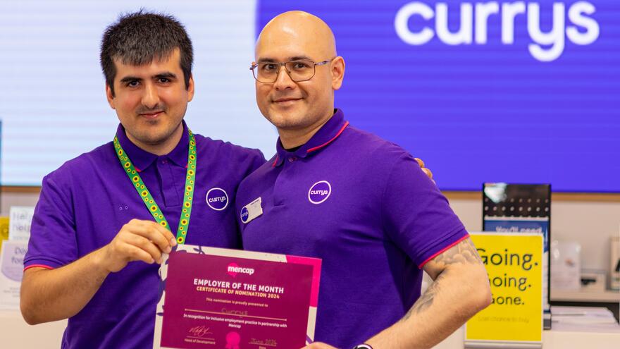 Niaz with his manager in Currys holding up a Mencap certificate