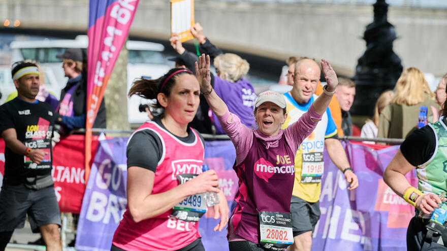 Female runner in Mencap vest with both arms in the air