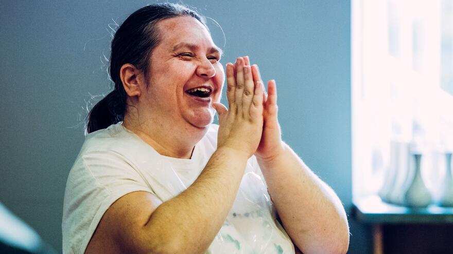 A woman smiling and putting her two hands together