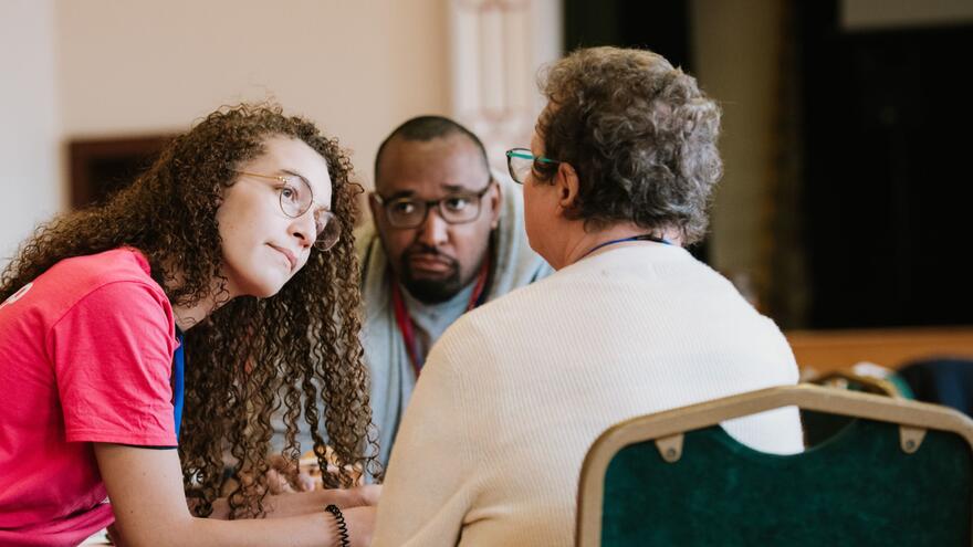 Three people sitting around a table talking