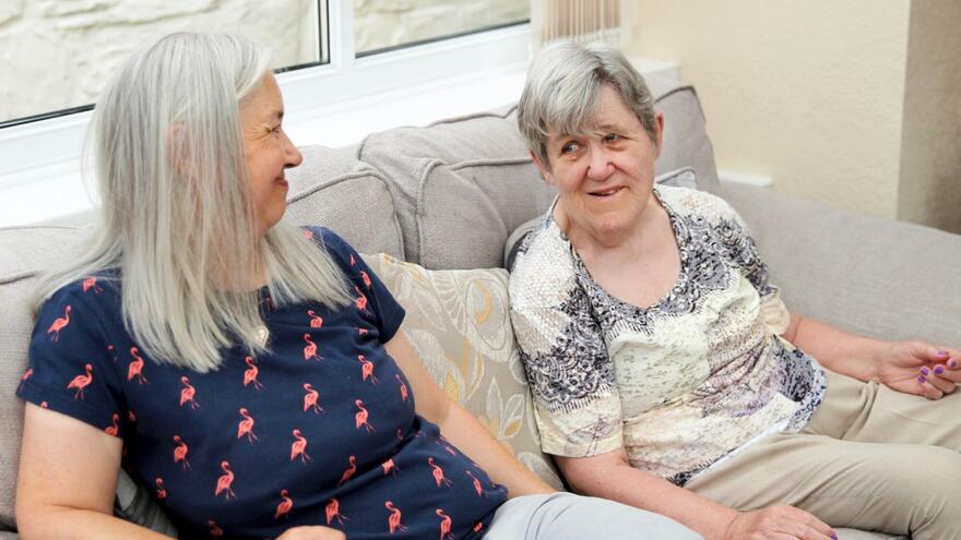 Two women sitting on a sofa talking