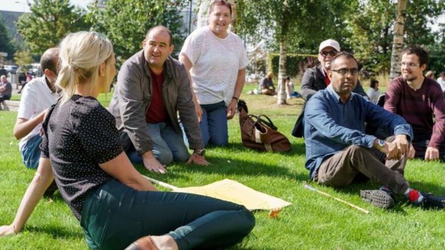 A group of people sitting on a grassy bank with activism and campaign signs on sticks