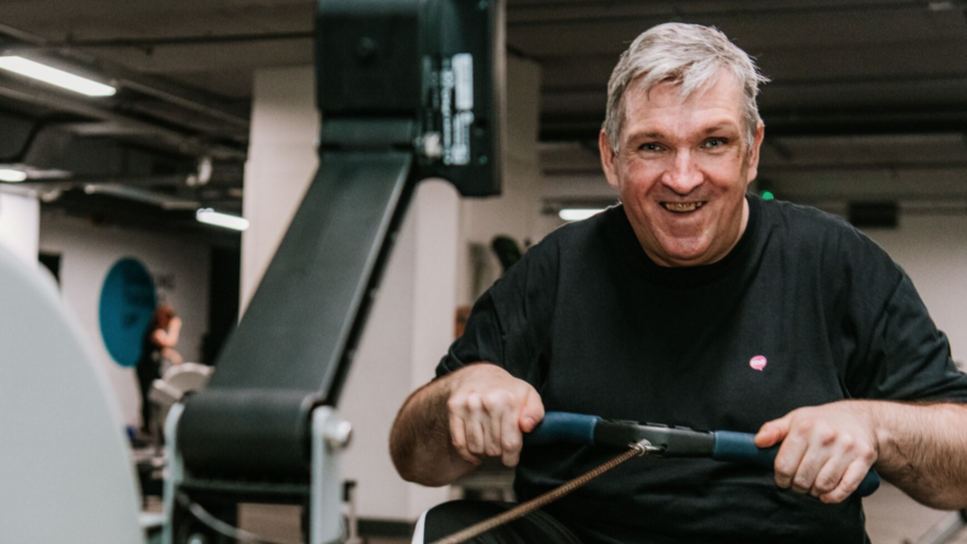 Man rowing on a rowing machine smiling 