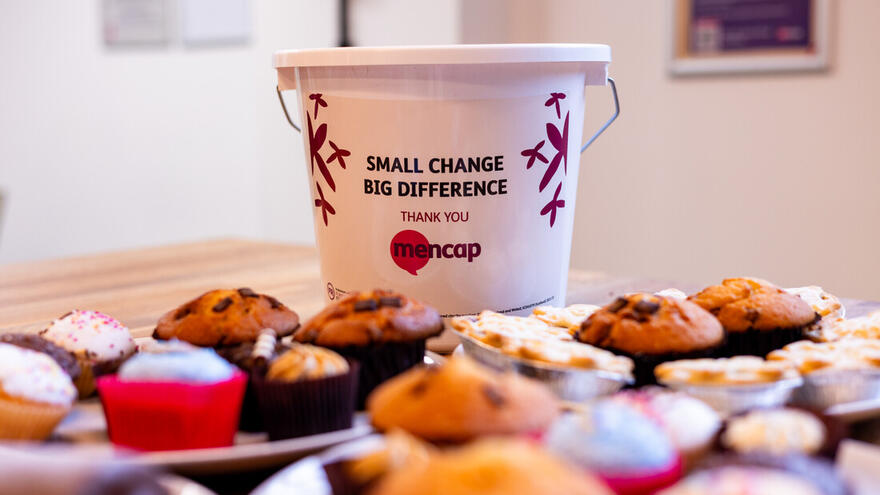Cakes on a table with a donation bucket behind them