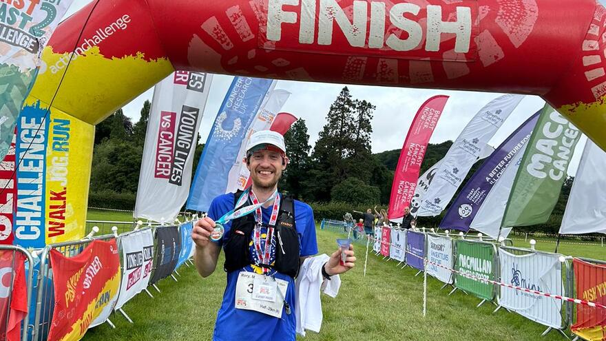 Man at the finish line of an ultra-challenge holding his medal.