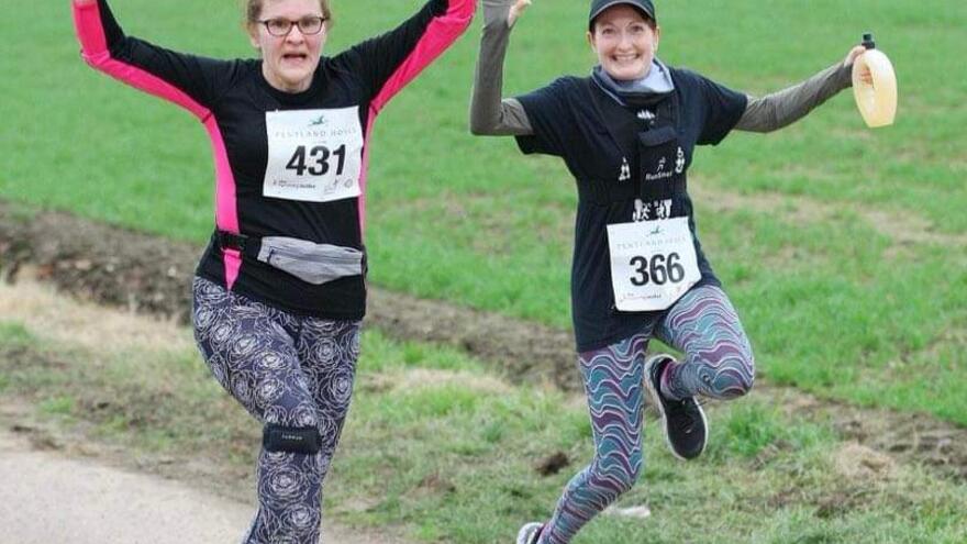 Two women jumping in the air whilst out running.