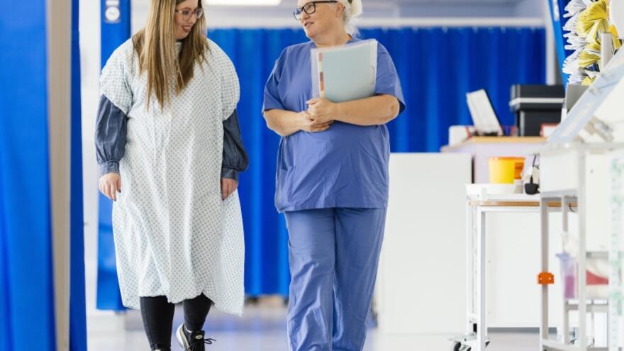 A patient and a doctor walking through a hospital ward talking