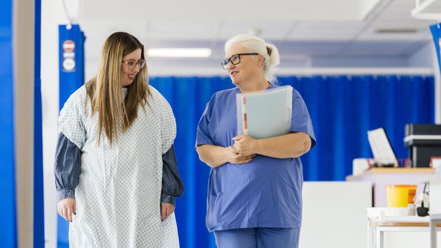 A patient and a doctor walking through a hospital ward talking