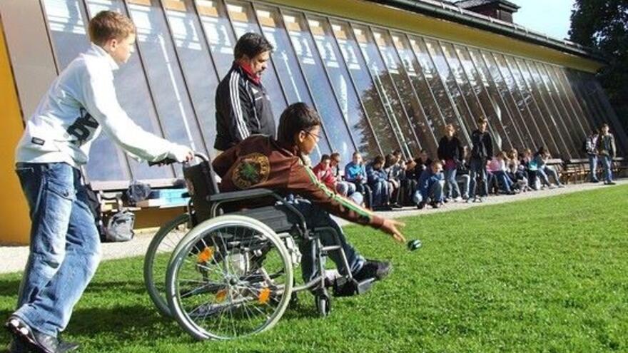 Child in wheelchair playing with a ball at school