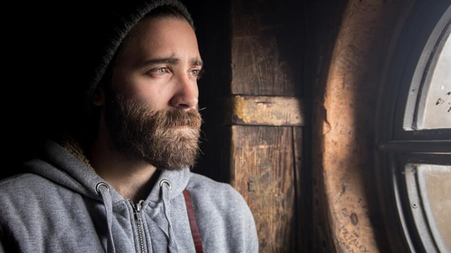 Man looking through a round window looking sad