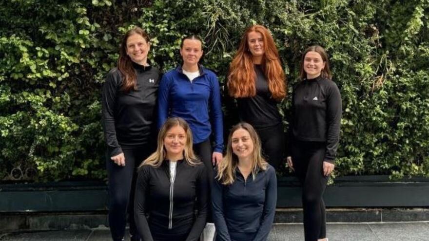 Group of six female runners in front of a hedge