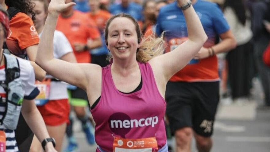 Woman running a race in a Mencap vest