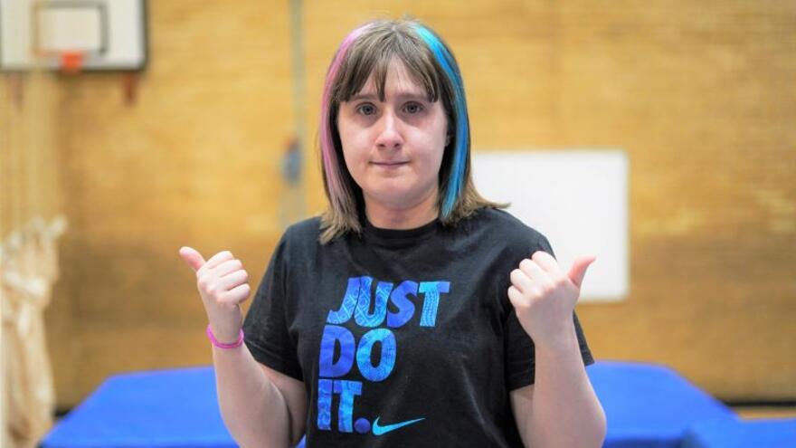 A young woman in a gym with her thumbs up
