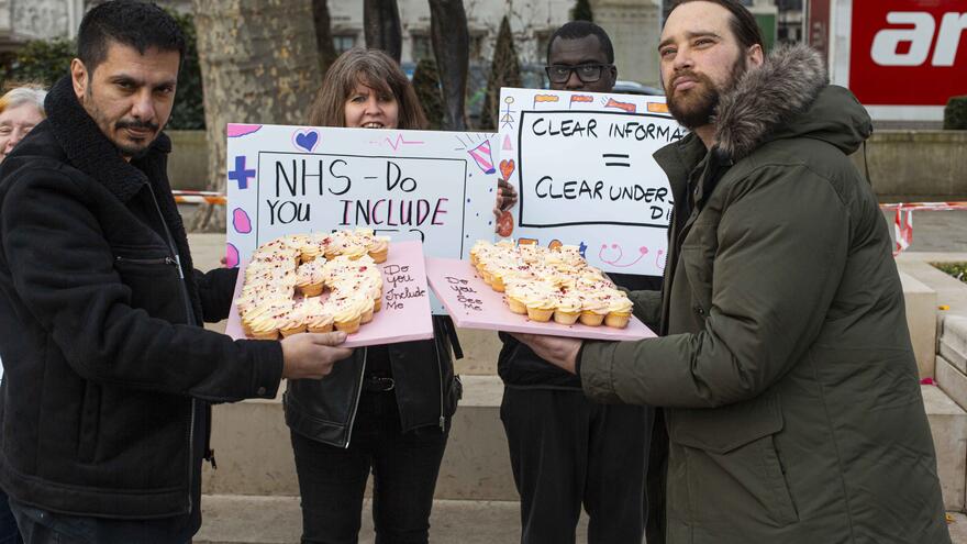 A group of four Treat Me Well campaigners hold a cake that reads 65 to give to parliament