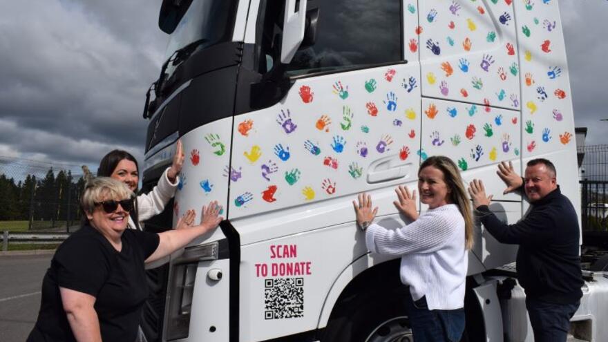 A group of people putting their hands on the decorated Dennison truck cab