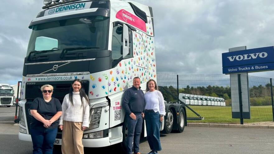 A group of people standing beside a decorated truck cab next to a Volvo sign