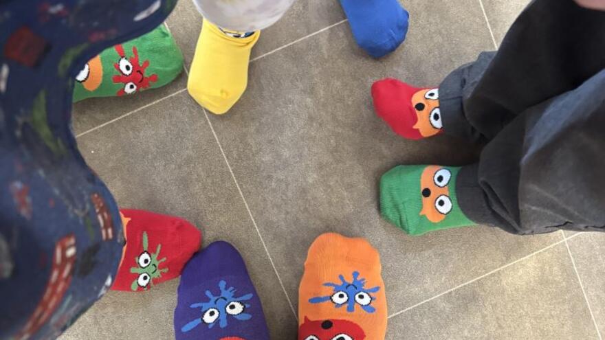A picture looking down at four peoples feet wearing odd socks - taken whilst raising money for Rock Your Socks 2025