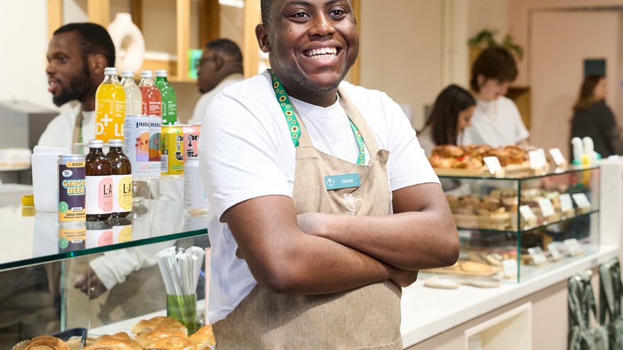 A man wearing an apron, smiling with his arms folded. 