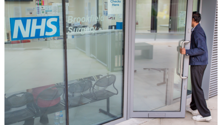 A photograph of a person entering an NHS building