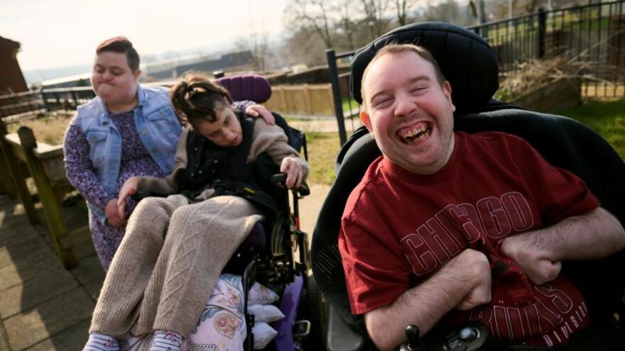 Two people in wheelchairs and one person next to them standing in a field