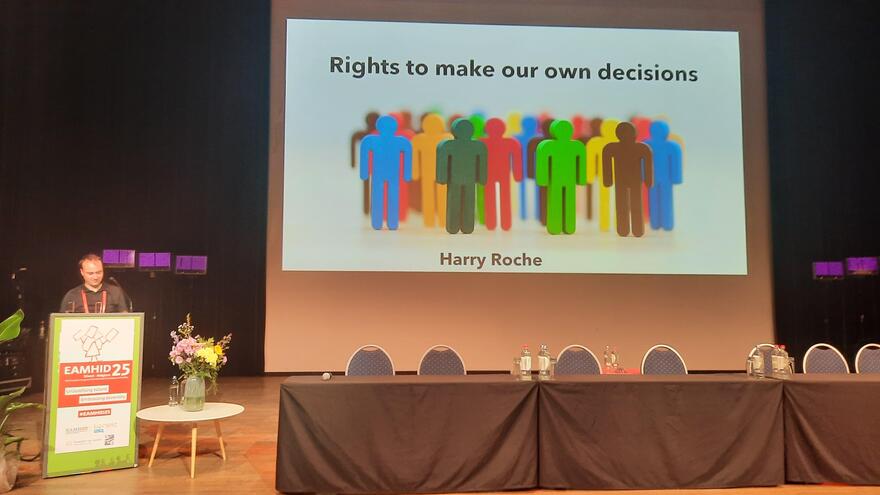 A man at a lectern giving a speech next to a screen that says "Right to 