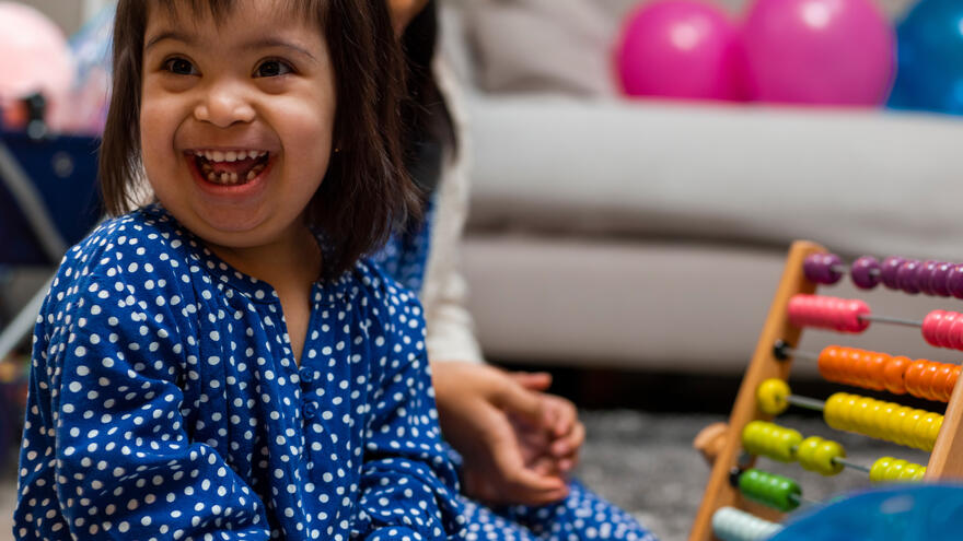 A young girl playing with an abacus whilst smiling