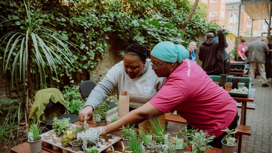 Two ladies working with potted plants in a community garden 