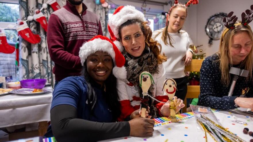 People around a craft table wearing Santa hats