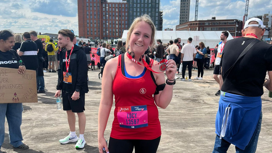 Lucy, standing with her medal after finishing the marathon.