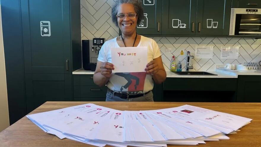A woman holding up a You Did It card designed by someone with a learning disability