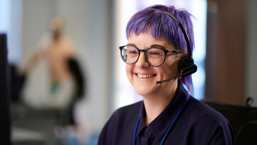A woman wearing a telephone headset smiling in an office
