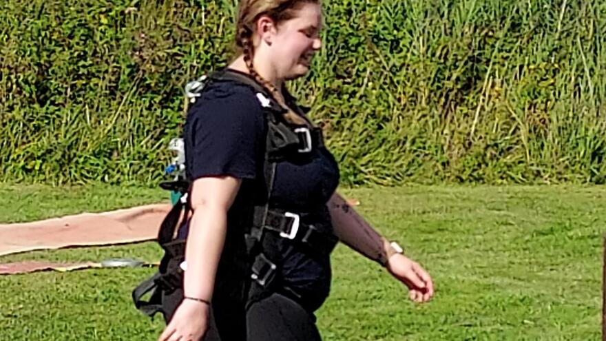Supporter wearing harness after skydive walking on grass
