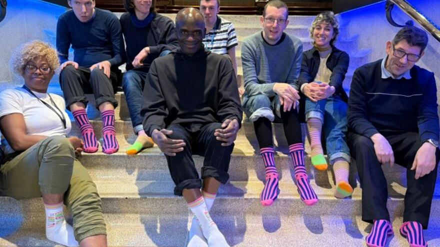 A group of young people sitting on steps inside a building showing their socks