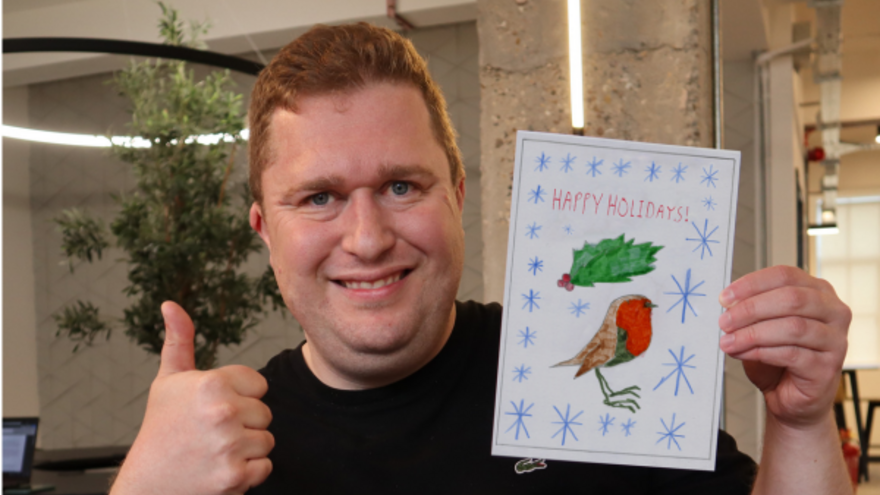 James, Mencap Fundraising Officer, holding a Christmas card that he designed