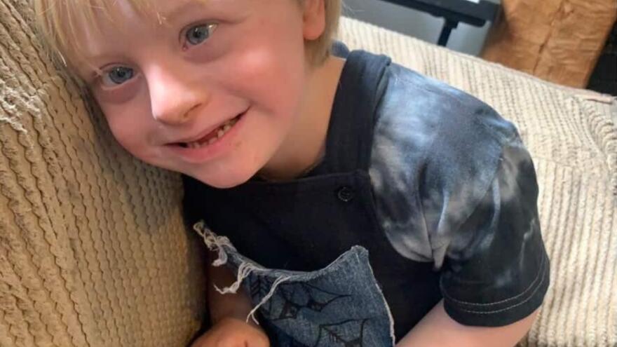 Little boy with blonde hair on a sofa smiling