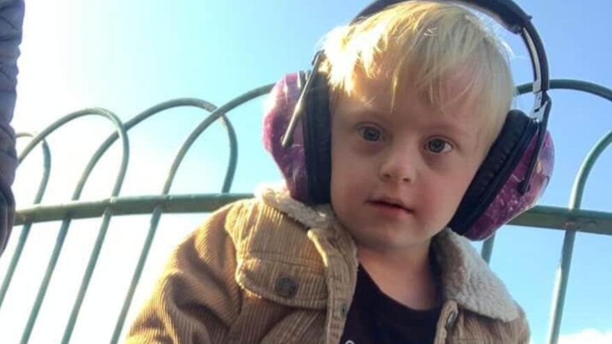 A little boy outside in a play park wearing ear defenders